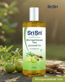 Sri Sri Tattva Bhringamalakadi Taila bottle with natural ingredients in the background