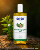 Sri Sri Tattva Brahmi Bhringraj Taila oil bottle with leaves in the background