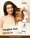 Woman with long hair holding a bottle of Sri Sri Tattva Hydrating Conditioner on a beige background