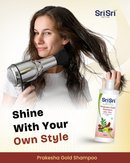 Woman using a hair dryer with Sri Sri Prakesha Gold Shampoo bottle displayed.