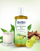 Bhringamalakadi Taila bottle with fresh amla, licorice root, a glass of milk and Bhringraj leaves