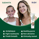 Woman and child with toothbrushes and Sri Sri Sudanta toothpaste tube with benifits