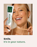 Woman smiling with Sudanta natural toothpaste and bamboo toothbrush