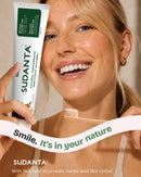 Woman smiling with Sudanta natural toothpaste and bamboo toothbrush
